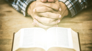 hands folded with bible open